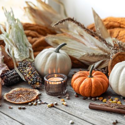 Autumn background with candles, pumpkins, corn and knitted element.