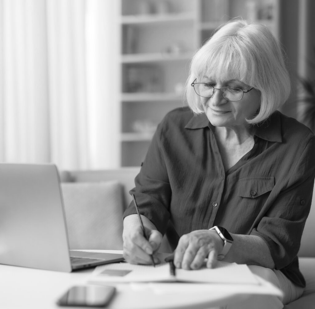 Retired Woman Reviewing Her Quarterly Investment Report and Taking Notes for Private Wealth Adviser