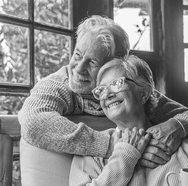 Happy Retired Couple in Looking Out Window in Home Confident in Their Insurance and the Risk Management it Provides